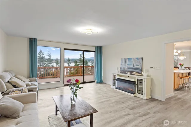 a living room with furniture large window and kitchen view