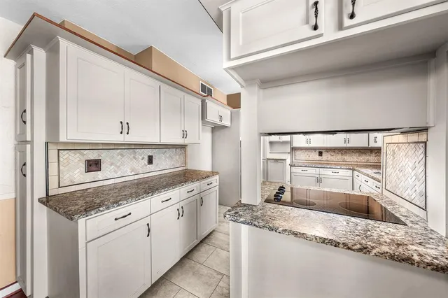 a kitchen with granite countertop white cabinets and stainless steel appliances