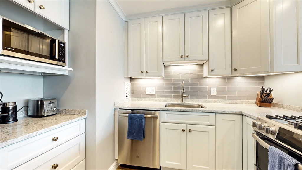 65 East India Row, Unit 24H Boston, MA 02110 - Photo 16 of 27 a kitchen with stainless steel appliances granite countertop a sink and a stove