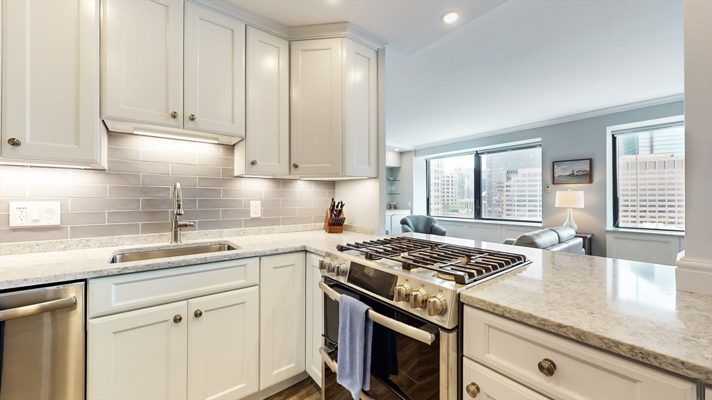 65 East India Row, Unit 24H Boston, MA 02110 - Photo 17 of 27 a kitchen with stainless steel appliances granite countertop a sink stove and cabinets