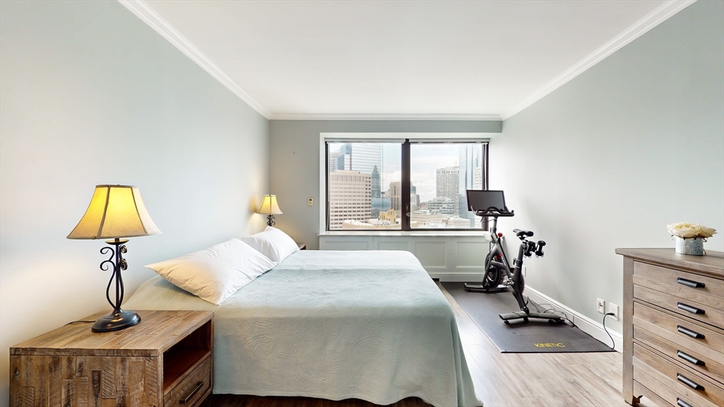 65 East India Row, Unit 24H Boston, MA 02110 - Photo 22 of 27 a bedroom with a bed and a chandelier