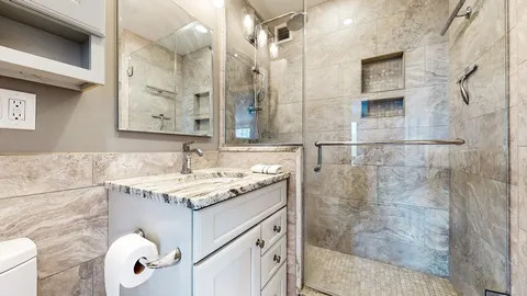 a bathroom with a sink vanity granite and shower