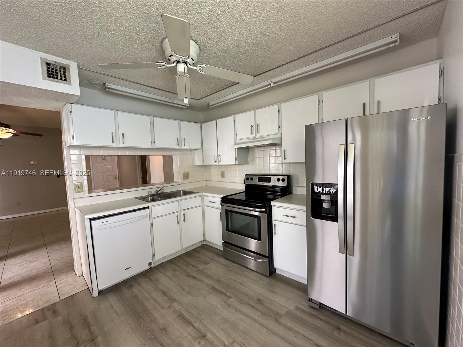 1024 South Independence Drive, Unit 1024A Homestead, FL 33034 - Photo 5 of 26 a kitchen with white cabinets and stainless steel appliances