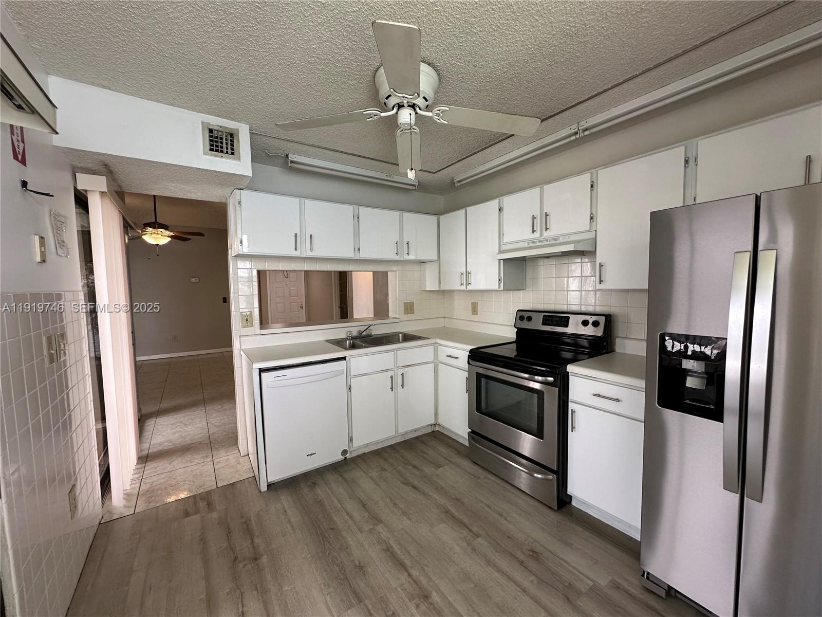 1024 South Independence Drive, Unit 1024A Homestead, FL 33034 - Photo 6 of 26 a kitchen with stainless steel appliances a refrigerator a stove a sink and white cabinets