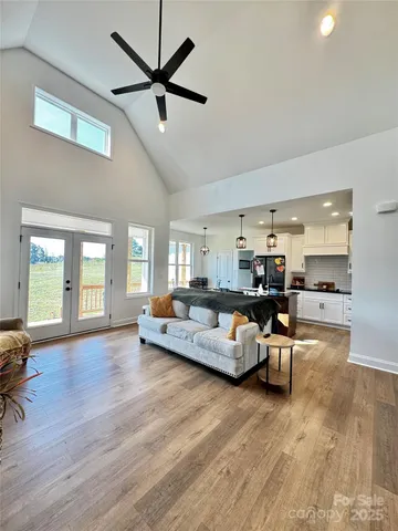 a living room with furniture kitchen view and a wooden floor