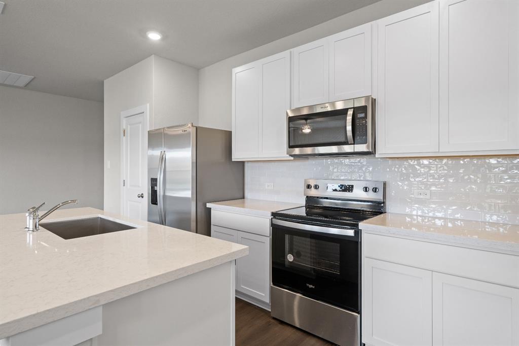 177 Sleep Hollow Jarrell, TX 76537 - Photo 8 of 24 Kitchen featuring white cabinetry, light-toned countertops, a stainless steel sink with a high-arc faucet, stainless steel appliances, and a textured white tile backsplash