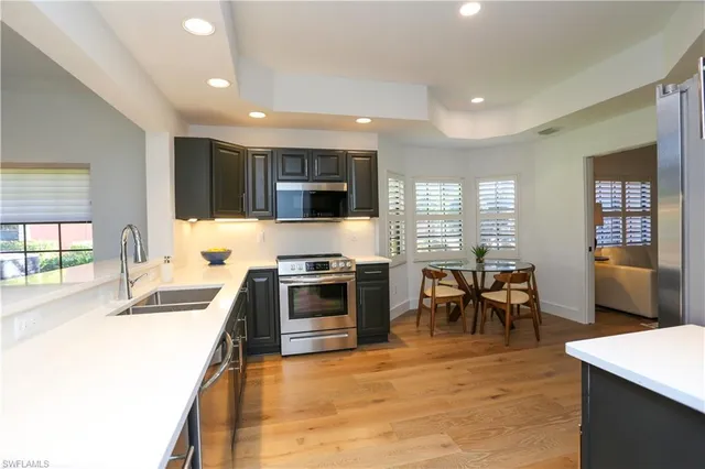 a kitchen with stainless steel appliances granite countertop a stove top oven a sink a dining table and chairs