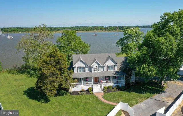a view of a white house with a big yard and potted plants
