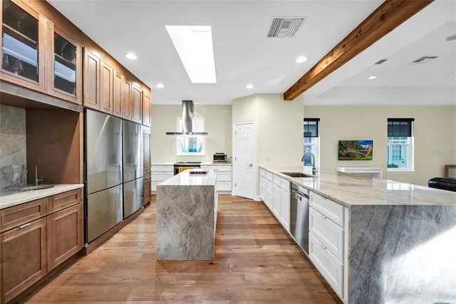a large kitchen with stainless steel appliances kitchen island granite countertop a large counter top and a stove