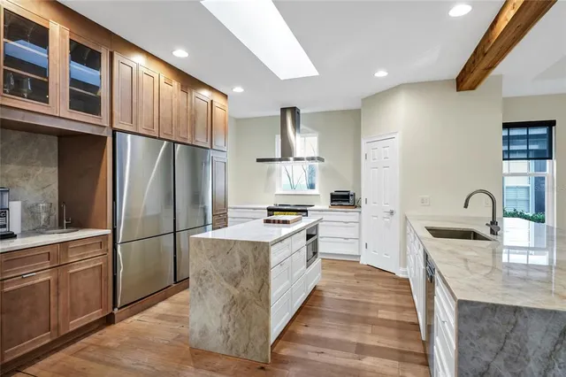 a kitchen with stainless steel appliances granite countertop a refrigerator a stove and a sink with wooden floors