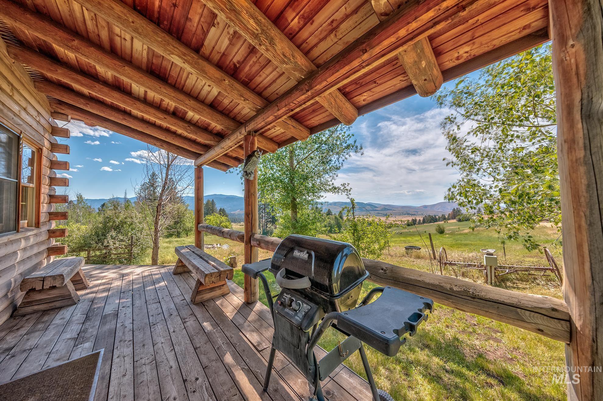 2150 Seid Creek Road Cambridge, ID 83610 - Photo 34 of 50 Rustic log cabin porch featuring a natural wood ceiling, exposed log beams, a wood-plank deck, and two built-in wooden benches