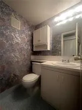 a bathroom with a granite countertop toilet a sink and mirror