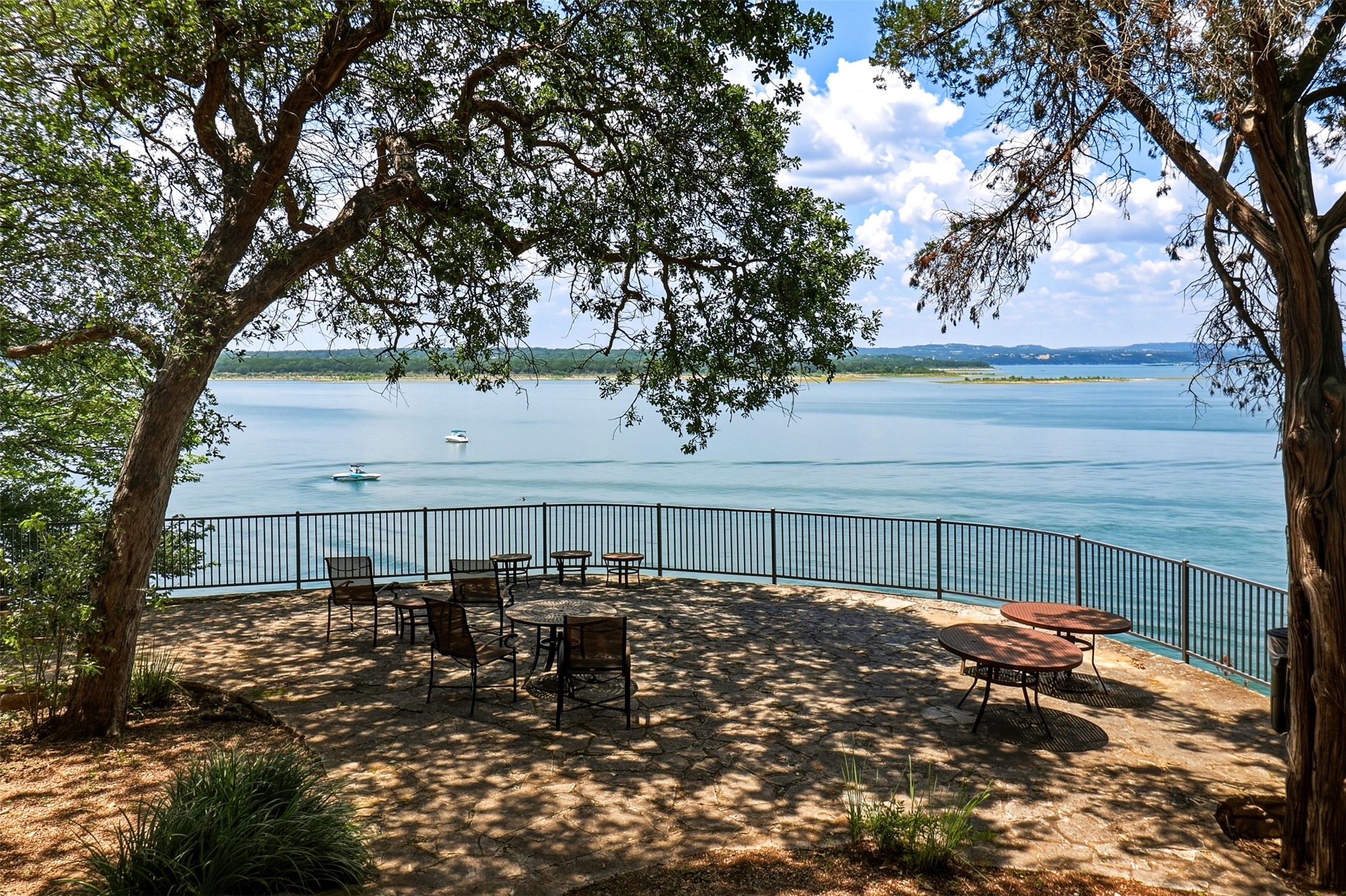 2918 Ranch Road 620, Unit 265 Austin, TX 78734 - Photo 32 of 40 A tranquil stone patio overlooks serene waters, framed by mature trees, offering a private outdoor retreat.