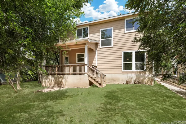 a view of a house with a yard and a large tree
