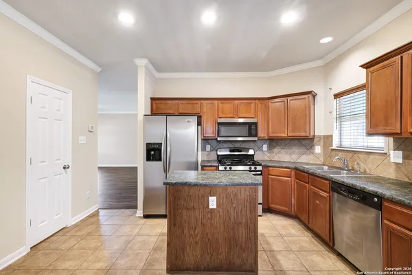 a kitchen with stainless steel appliances granite countertop a sink a stove a refrigerator cabinets and a center island