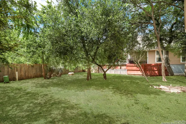 a view of backyard with table and chairs and trees