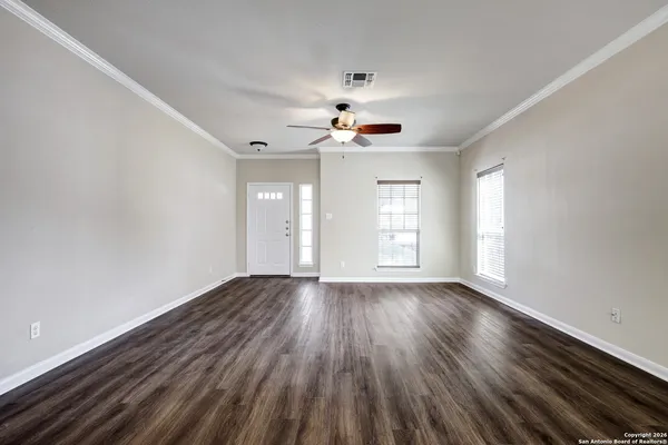 a view of an empty room with wooden floor and a window