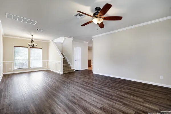 an empty room with wooden floor fan and windows