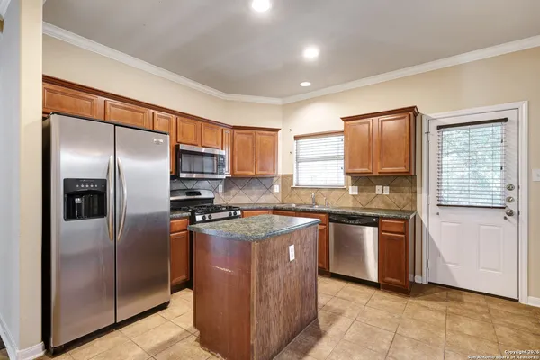 a kitchen with stainless steel appliances granite countertop a refrigerator a sink a stove and island