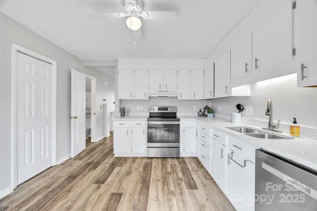 a kitchen with stainless steel appliances a stove a sink and white cabinets