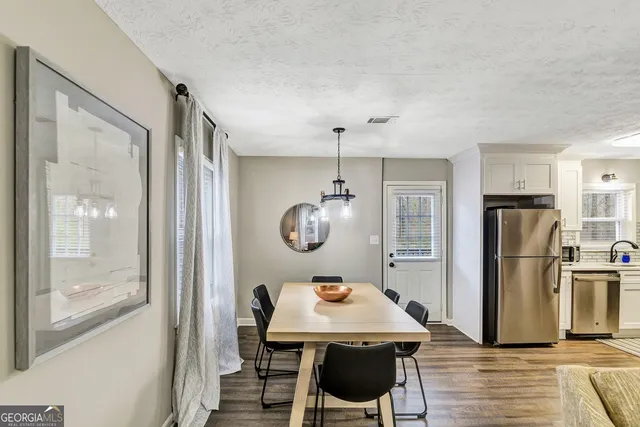 a room with a table chairs and refrigerator