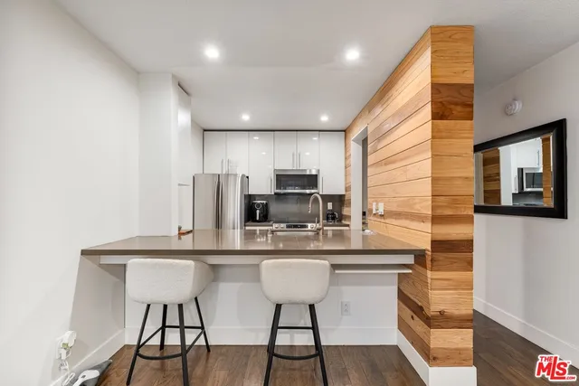 a kitchen with stainless steel appliances a dining table chairs microwave and sink