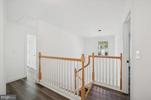 a view of a hallway with white walls and wooden floor