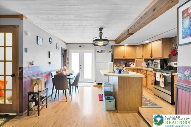 a kitchen with stainless steel appliances kitchen island granite countertop a refrigerator a stove top oven a dining table and chairs with wooden floor