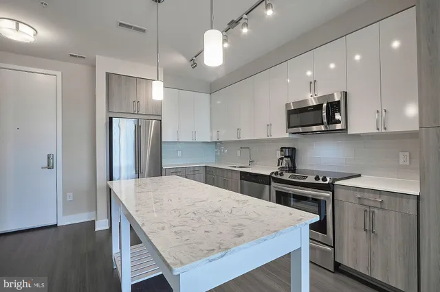 a kitchen with kitchen island a sink stainless steel appliances and wooden floor