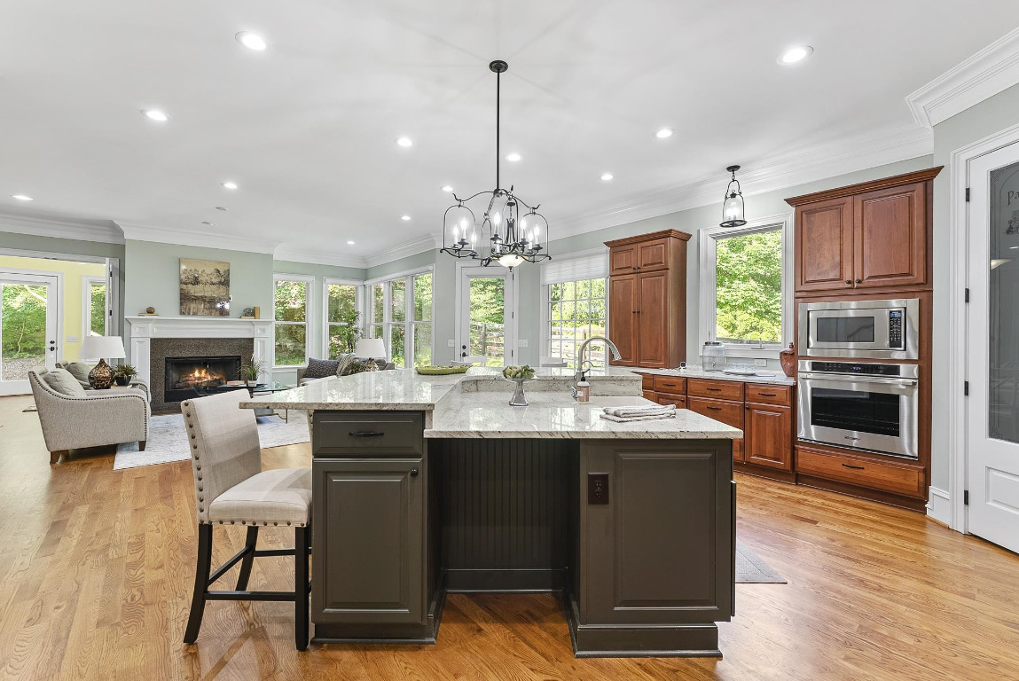 a kitchen with stainless steel appliances granite countertop a table chairs stove and refrigerator