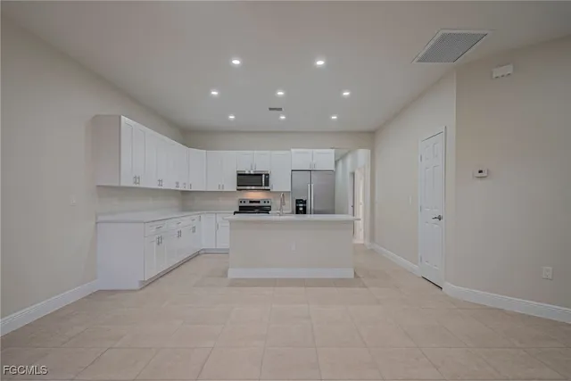 a open kitchen with white cabinets and stainless steel appliances