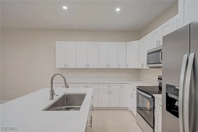 a kitchen with stainless steel appliances a refrigerator sink and white cabinets