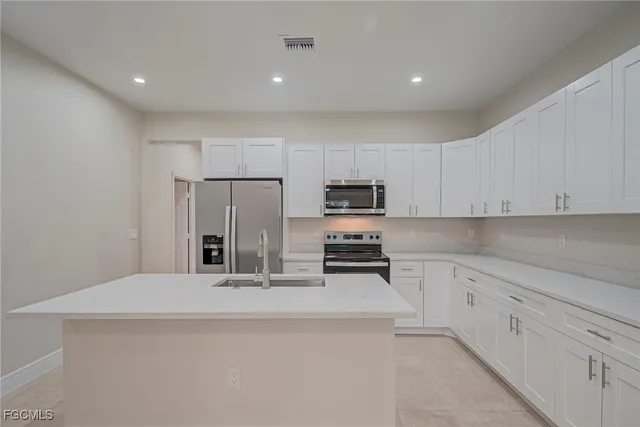 a kitchen with white cabinets and stainless steel appliances