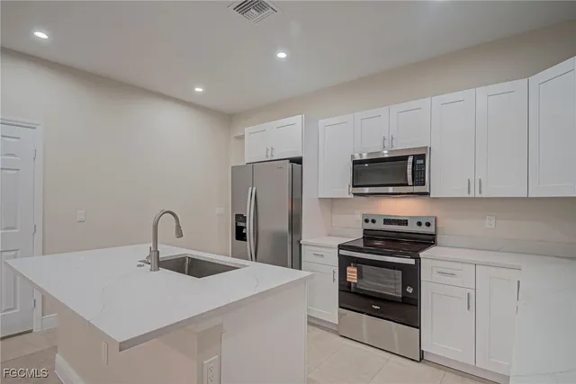 a kitchen with stainless steel appliances a sink dishwasher a refrigerator and white cabinets
