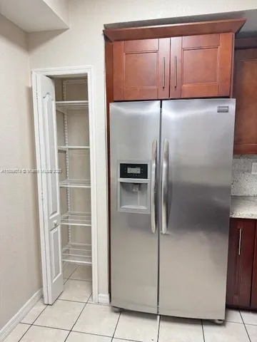 a kitchen with a refrigerator and wooden cabinets