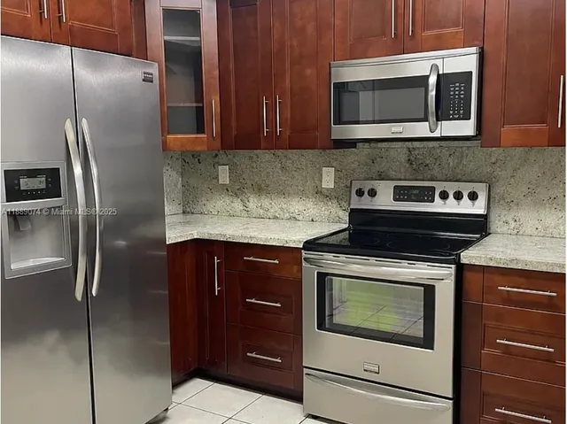 a kitchen with stainless steel appliances granite countertop a stove microwave and refrigerator