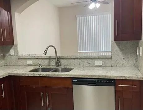 a kitchen with granite countertop a sink stainless steel appliances and a window