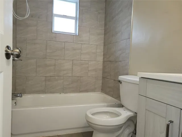 a bathroom with a granite countertop toilet and a bathtub