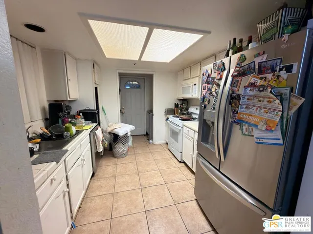 a kitchen with a refrigerator and white cabinets