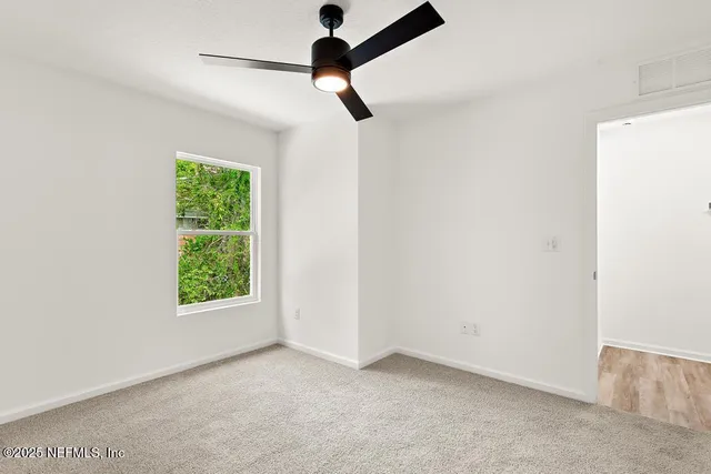 an empty room with a window and a ceiling fan