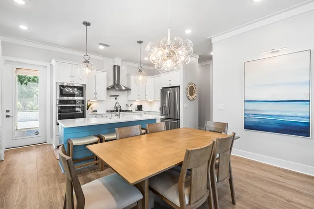 a kitchen with stainless steel appliances kitchen island granite countertop a table chairs and a refrigerator