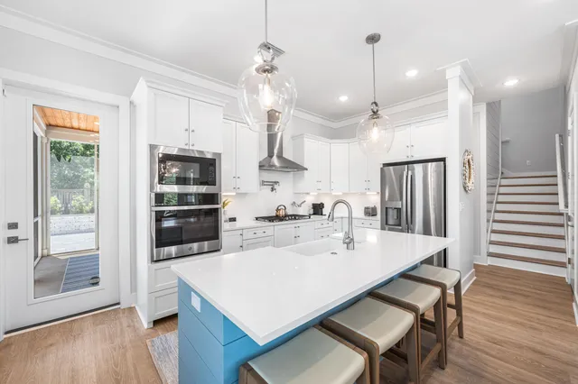 a kitchen with stainless steel appliances kitchen island granite countertop a table chairs and a refrigerator