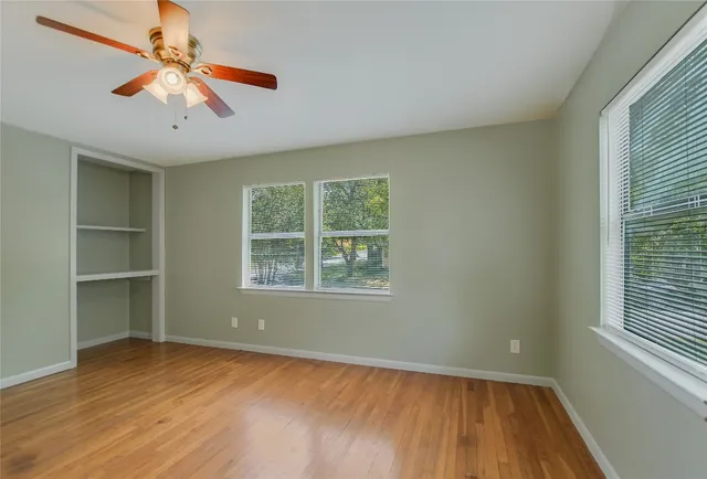 a view of an empty room with a window and wooden floor