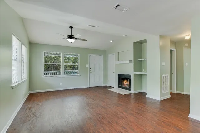 an empty room with fireplace wooden floor and windows
