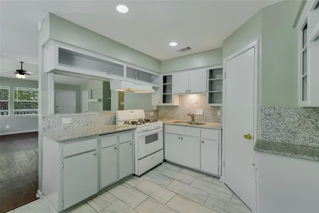 a kitchen with granite countertop white cabinets and white appliances