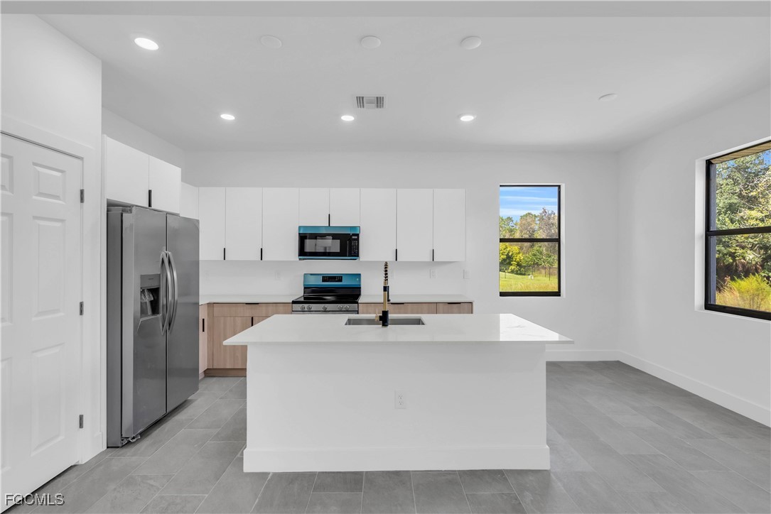 3224 53rd Street West Lehigh Acres, FL 33971 - Photo 5 of 22 a kitchen with stainless steel appliances a refrigerator sink and stove