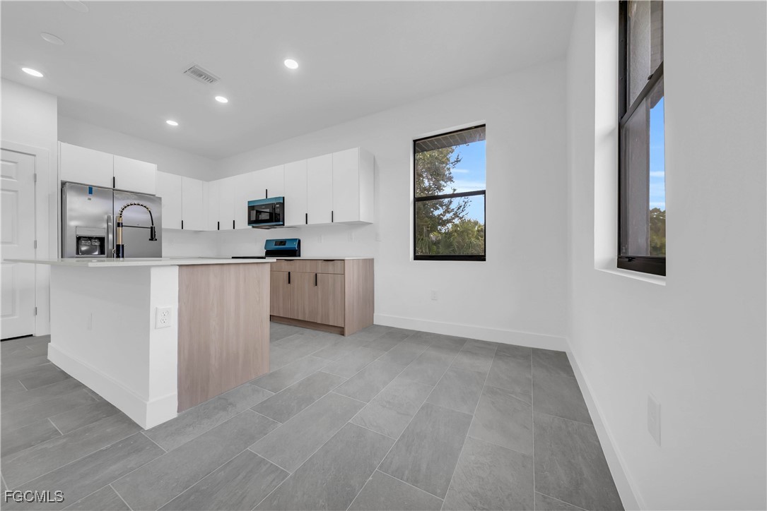 3224 53rd Street West Lehigh Acres, FL 33971 - Photo 5 of 14 a kitchen with white cabinets and sink