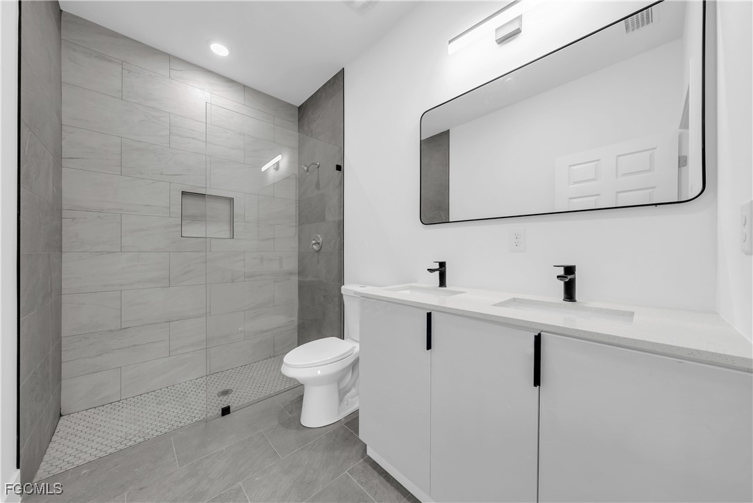 3224 53rd Street West Lehigh Acres, FL 33971 - Photo 7 of 14 a bathroom with a sink a toilet and mirror