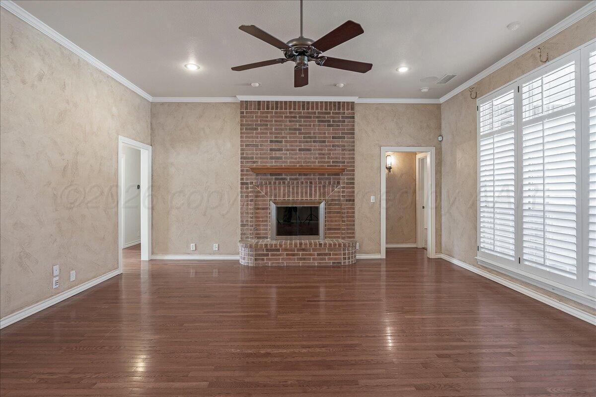 5823 Nicholas Circle Amarillo, TX 79109 - Photo 8 of 31 an empty room with wooden floor a ceiling fan a fireplace and windows