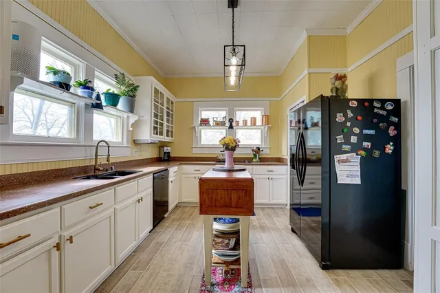 a kitchen with stainless steel appliances granite countertop a refrigerator a sink dishwasher a dining table and chairs with wooden floor